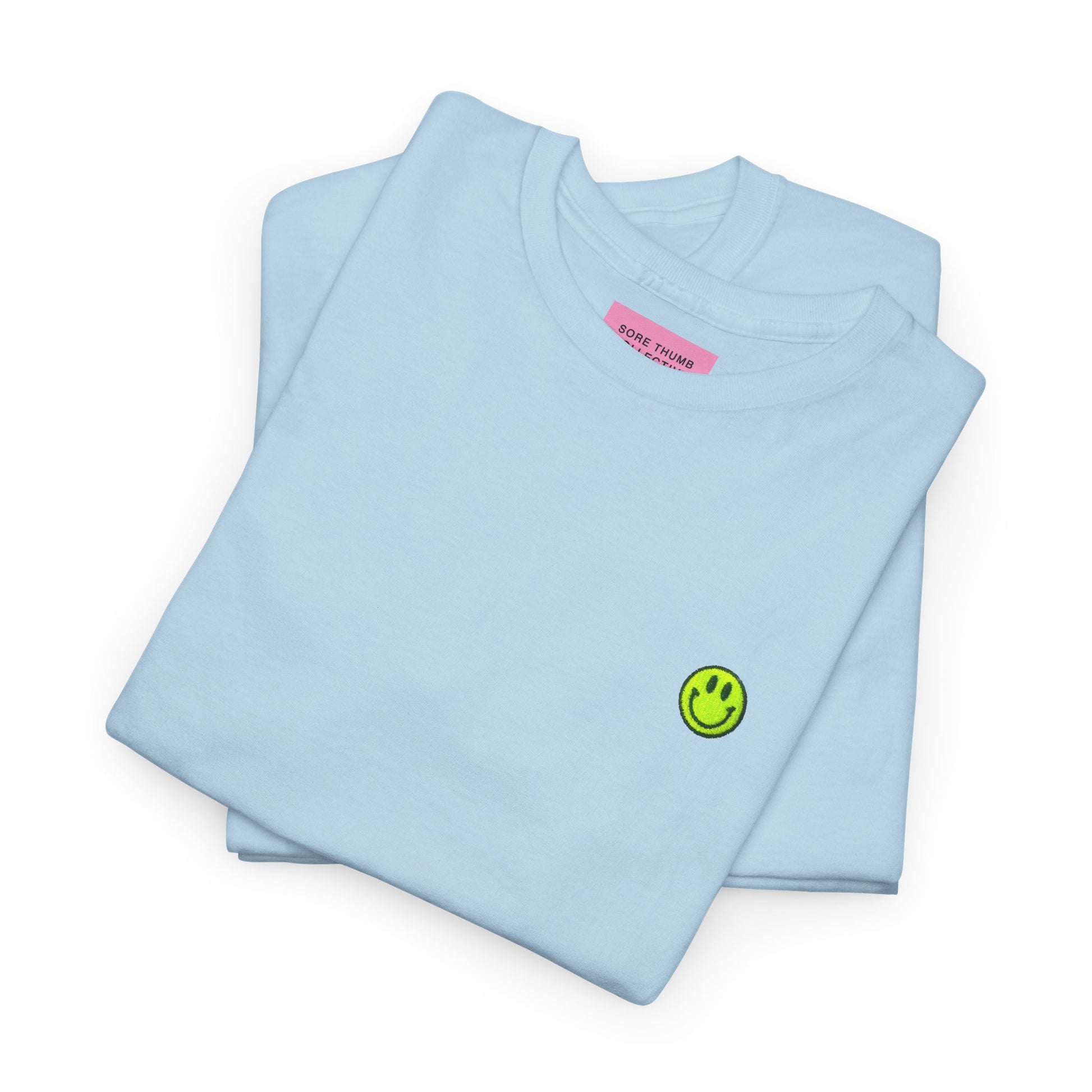 Light blue t-shirt with a smiley face design and a pink label on a white background