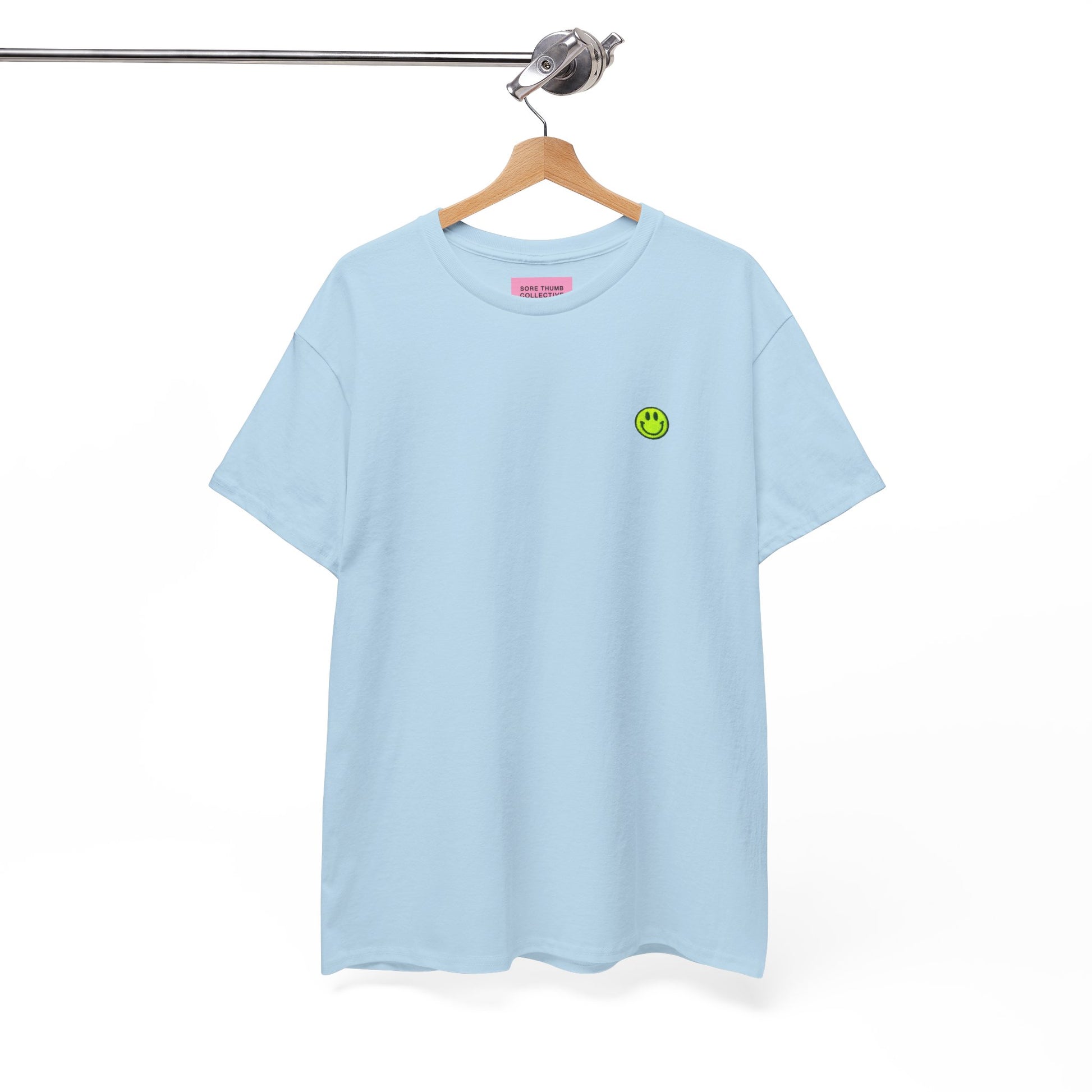 Light blue t-shirt with a green smiley face logo on a hanger against a white background