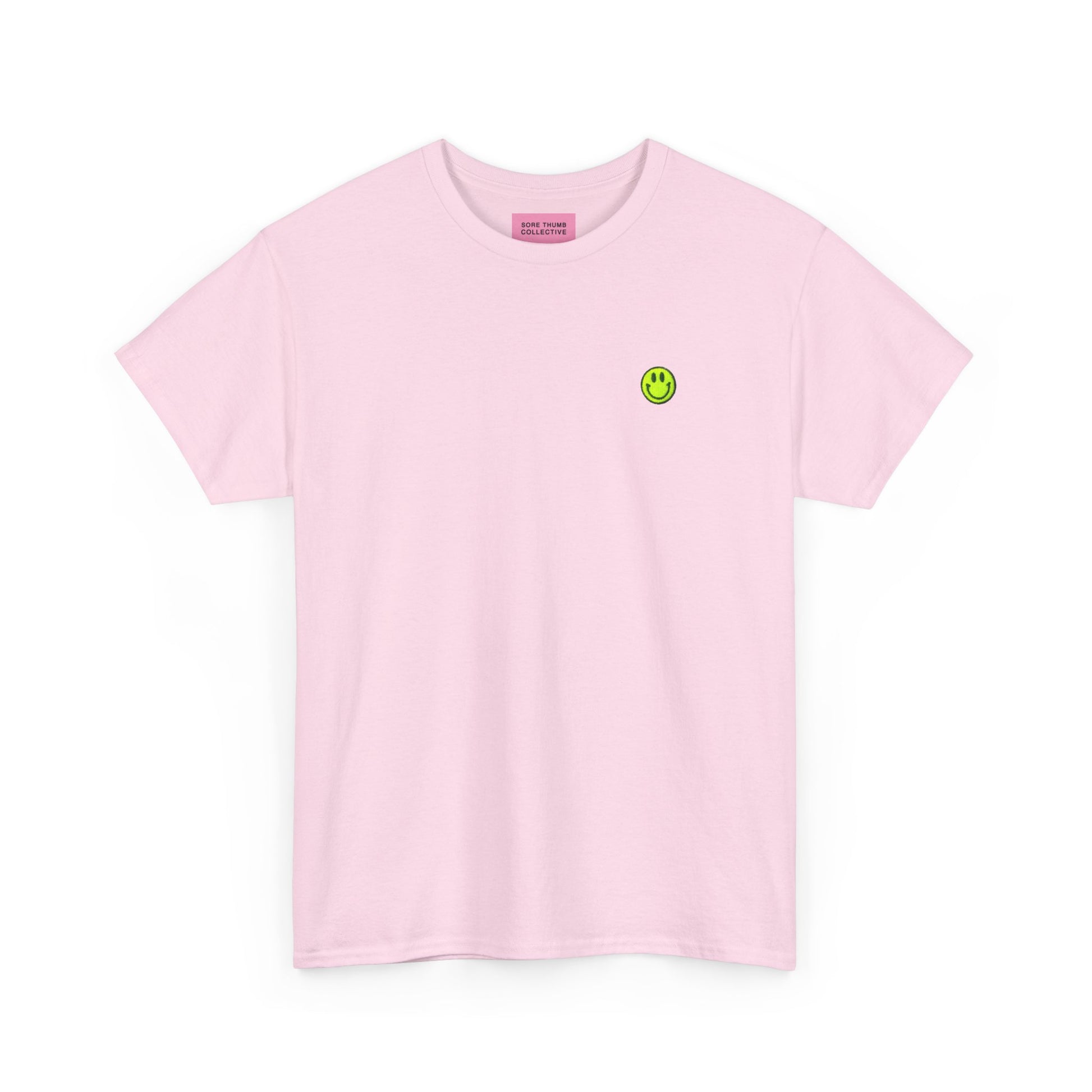 Pink t-shirt with a small green smiley face logo on a white background