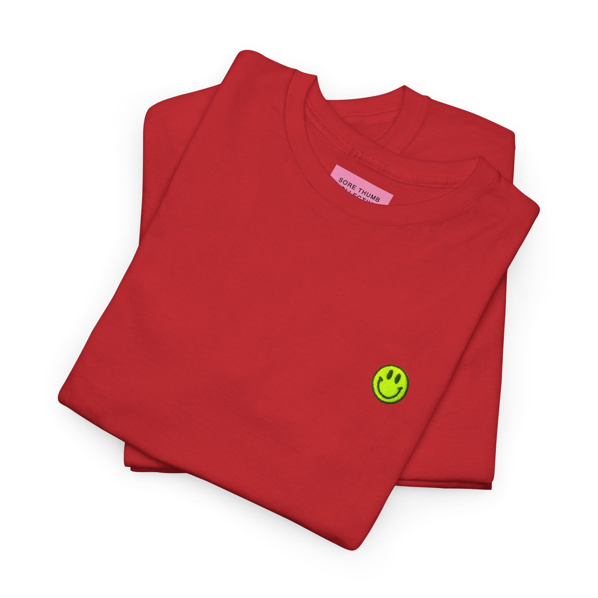 Folded red sweatshirt with a green smiley face logo on a white background