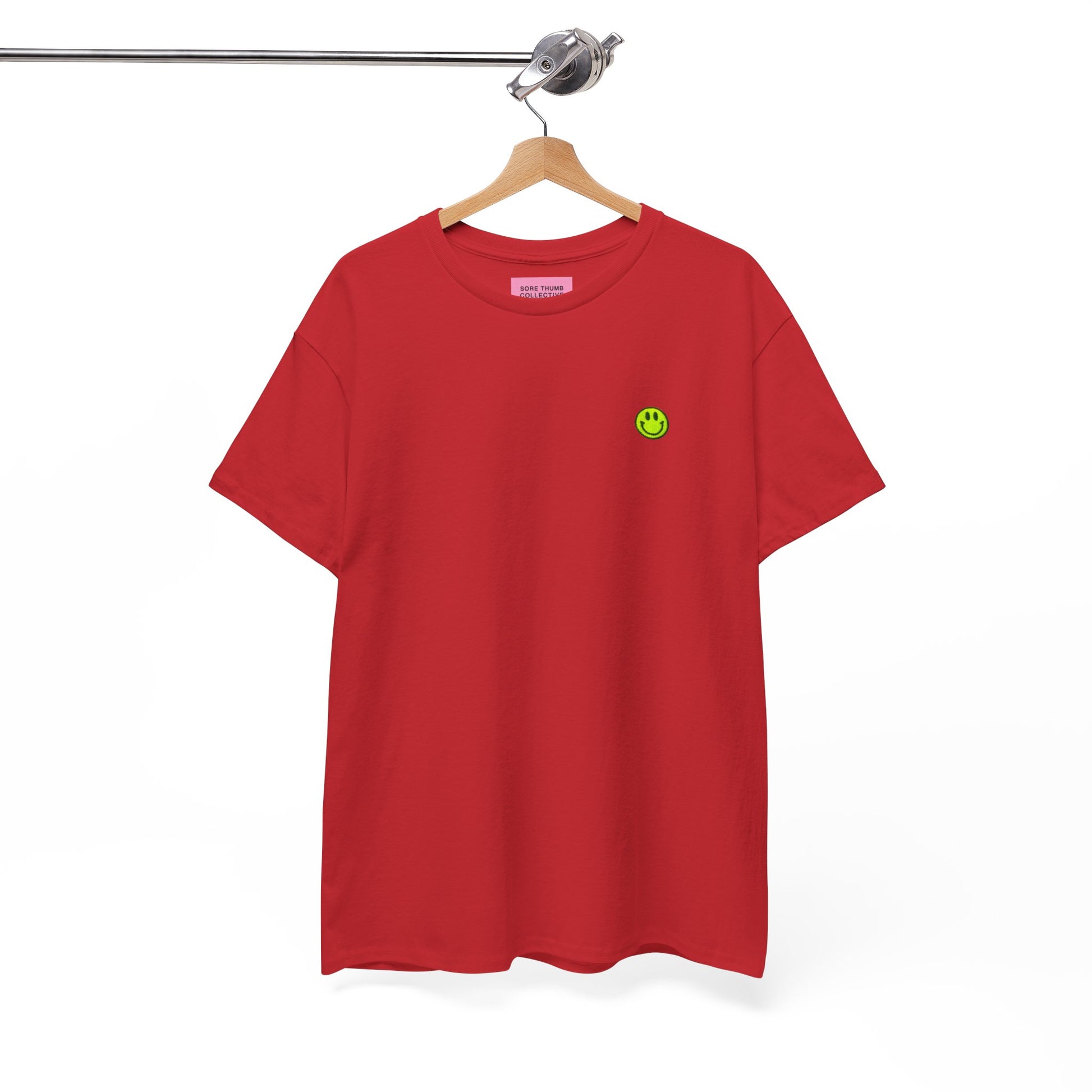 Red t-shirt with a small smiley face logo on a hanger against a white background