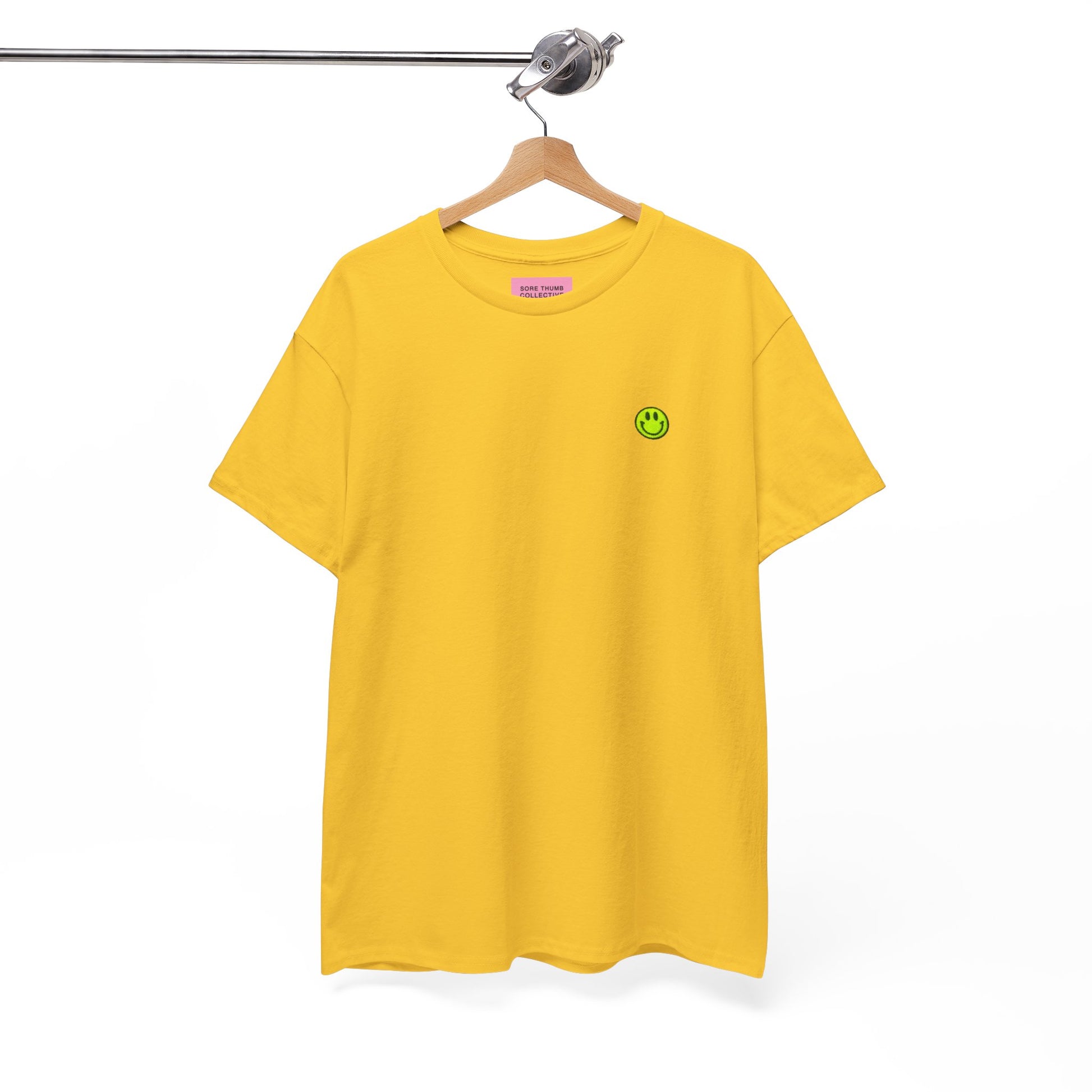Yellow t-shirt with a green smiley face logo on a hanger against a white background
