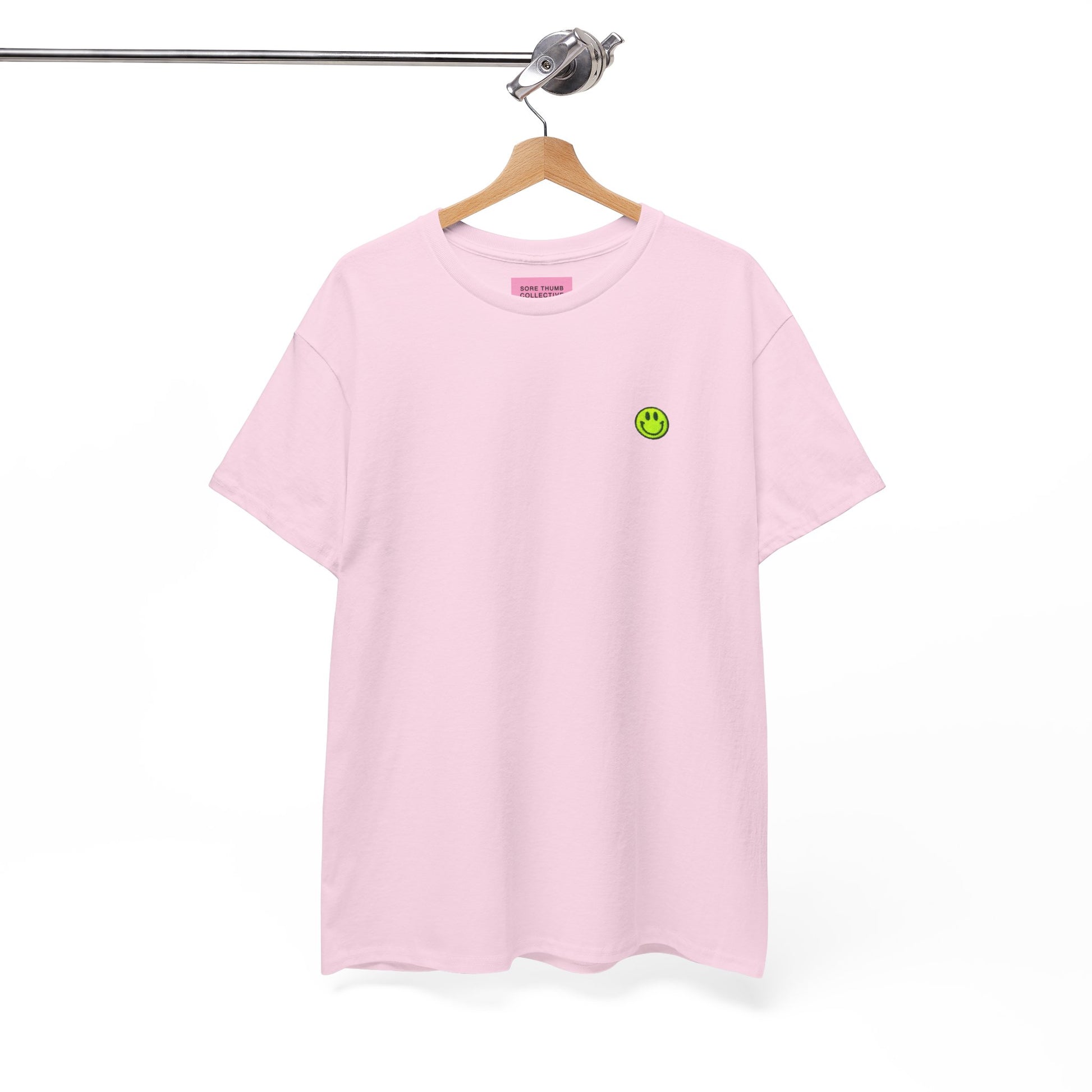 Pink t-shirt with a green smiley face on a hanger against a white background
